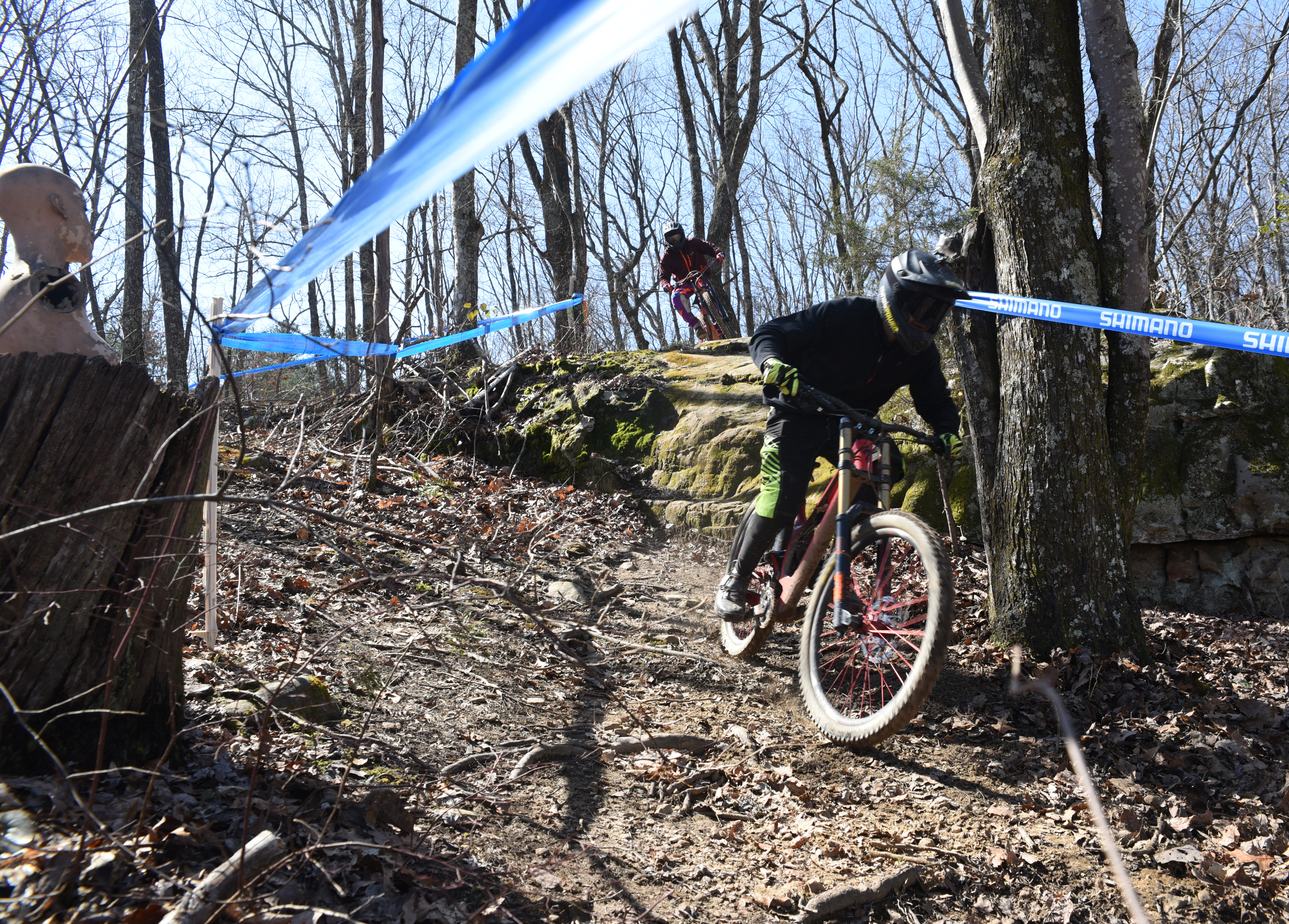 Blue tape lines the pro trail atop Sequatchie Mountain as Max Morgan, 17, and Kai Nishinu take the first rock jump in practice Friday from an elevation of 1,700 feet. The upper torso of a mannequin sits atop a stump, at left, as trail decoration. according to Troy Roberts at the TTC Gravity Park.