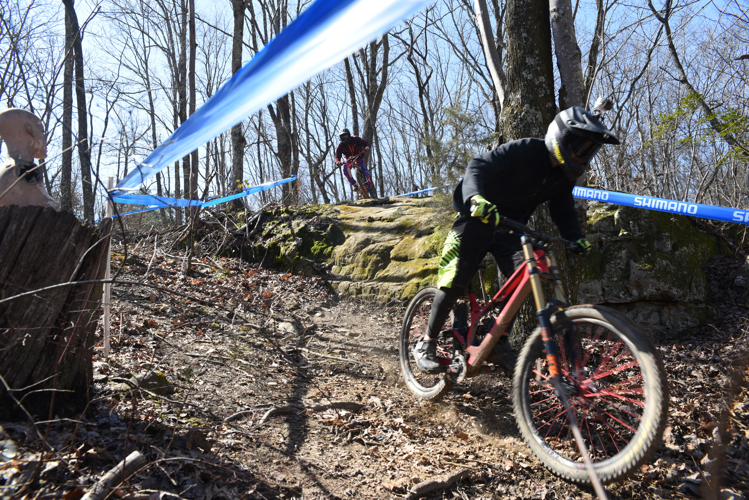 Blue tape lines the pro trail atop Sequatchie Mountain as Max Morgan, 17, and Kai Nishinu take the first rock jump in practice Friday from an elevation of 1,700 feet. The upper torso of a mannequin sits atop a stump, at left, as trail decoration. The trail drops 1,050-feet in 1.1-miles into Coppinger Cove in Marion County, according to Troy Roberts at the TTC Gravity Park.