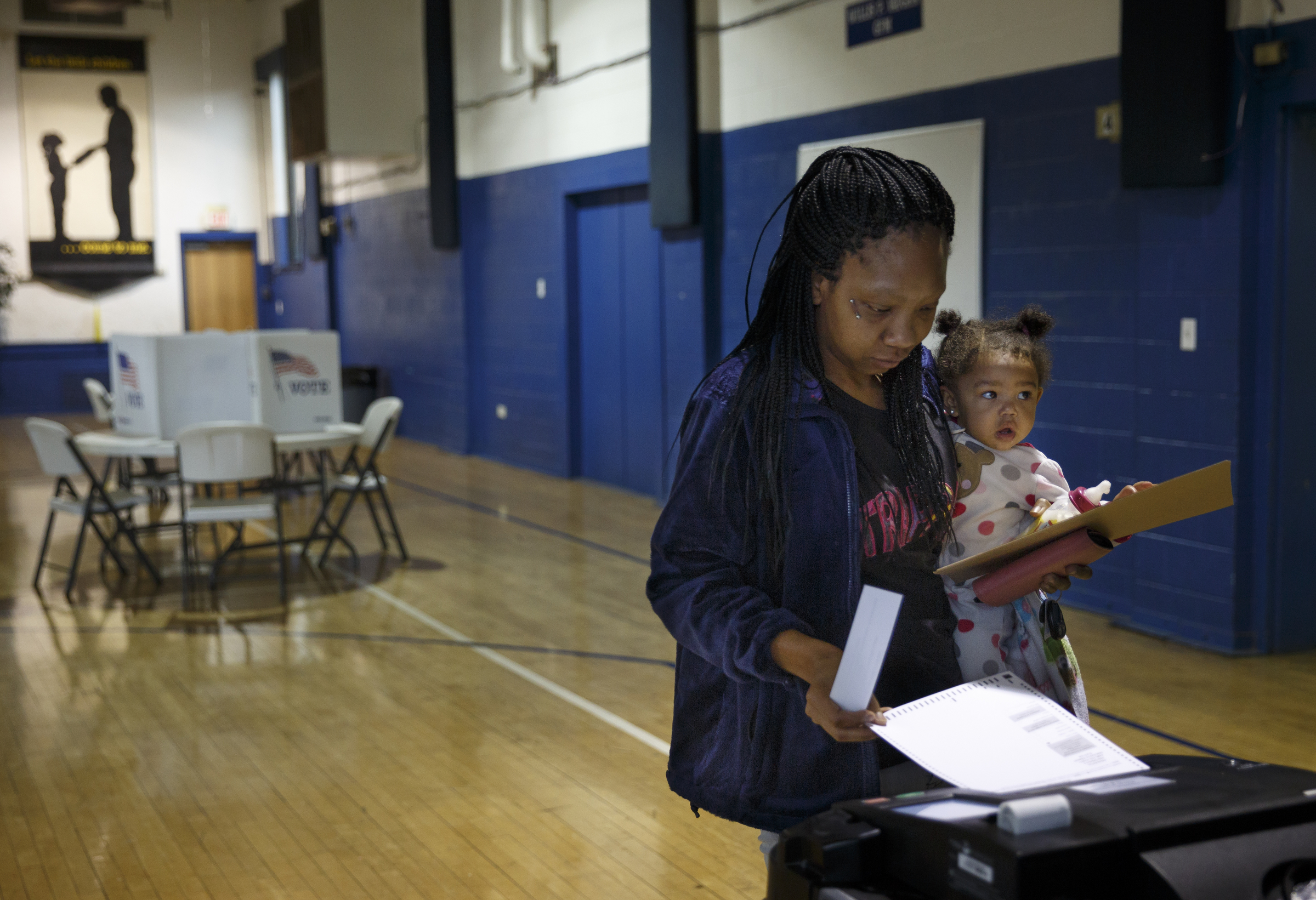 Tiffany Reid holds Kayleigh Patterson as she places her ballot in a voting machine after voting in the Super Tuesday primary election at the Bethlehem Center polling location on Tuesday, March 1, 2016, in Chattanooga, Tenn.