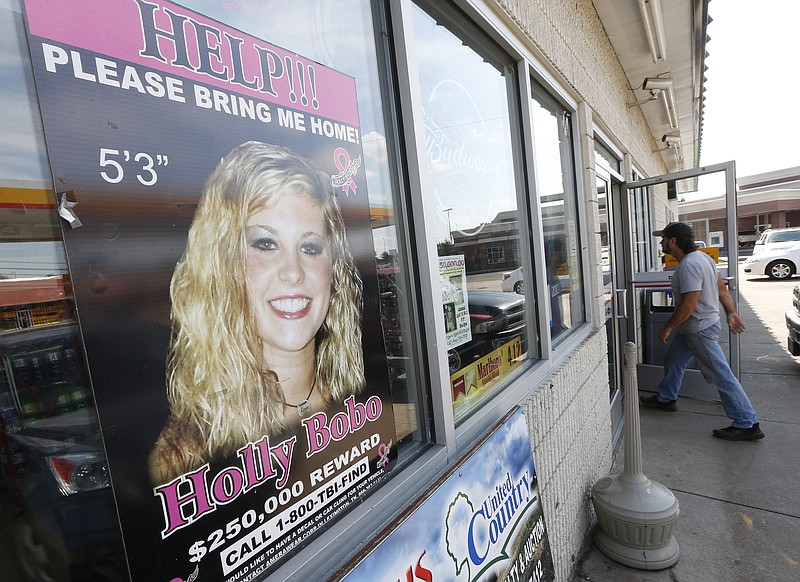
              FILE - In this Sept. 9, 2014 file photo, a poster offering a reward for information in the disappearance of Holly Bobo, is displayed in a store window in Parsons, Tenn.  A Tennessee judge has set a target trial date in early 2017 for at least one of three men charged with murder in the 2011 disappearance of Bobo.  (AP Photo/Mark Humphrey, File)
            