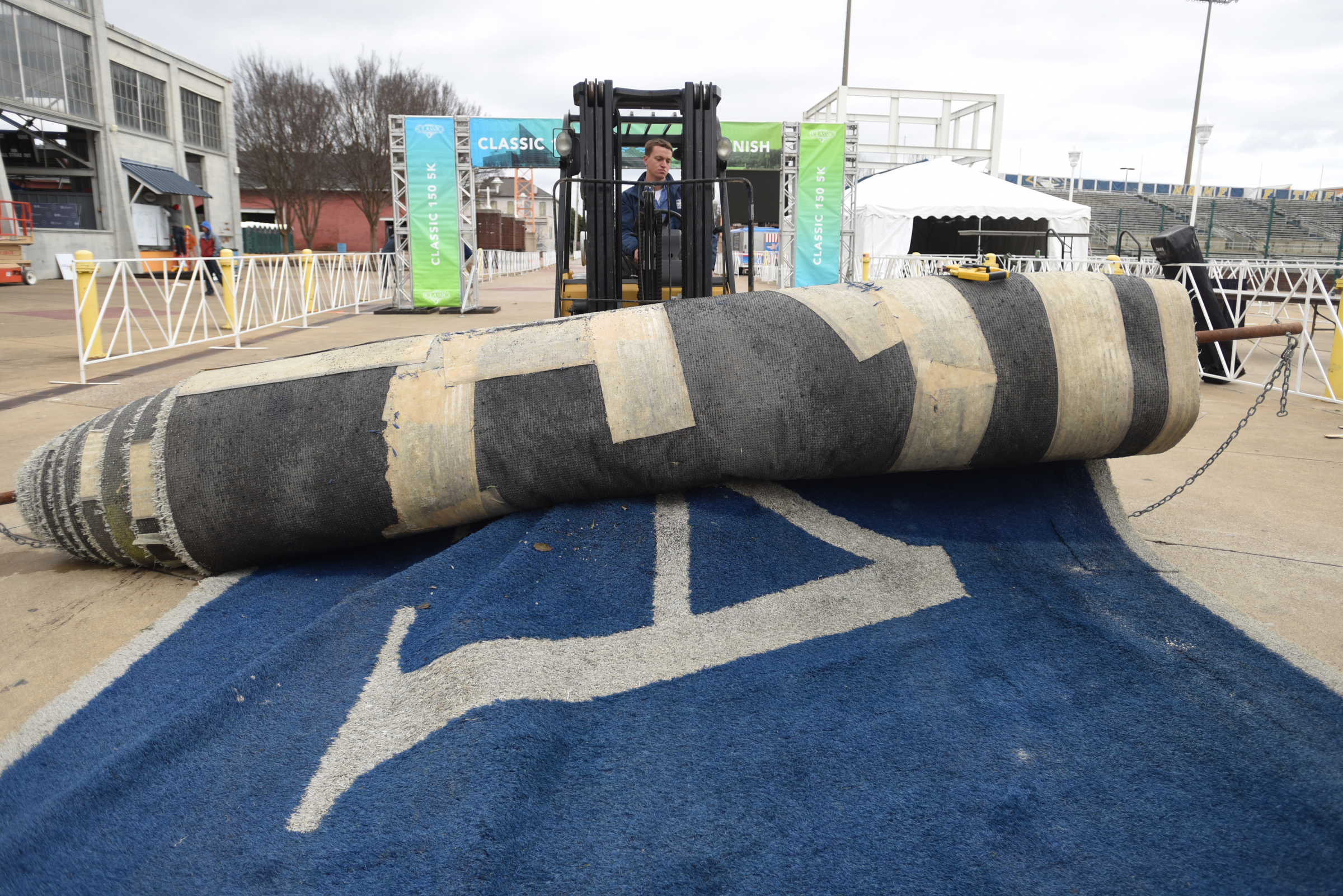 Brian Wright raises a roll of turf while setting up Friday, March 4, 2016 for Sunday's inaugural Erlanger Chattanooga Marathon at First Tennessee Pavilion. The Chattanooga portion of Finley Stadium's old turf will be rolled out at the other side of the finish line.