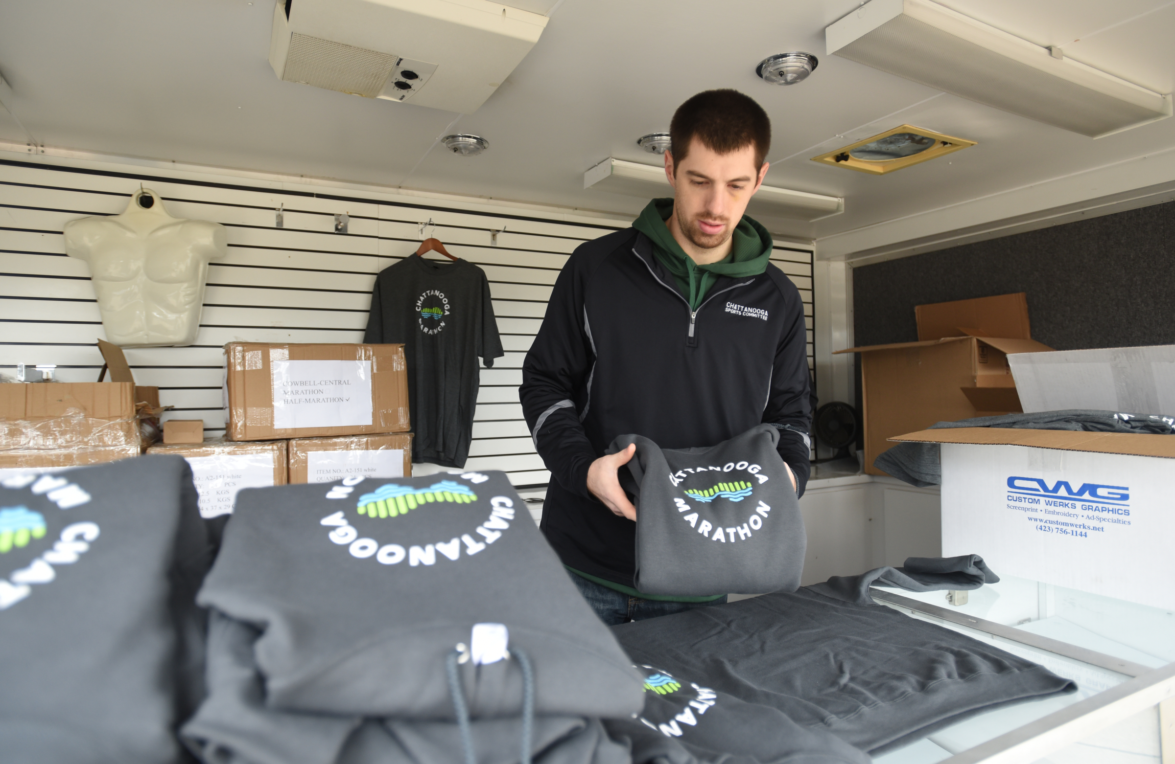 Brant Donlon folds shirts while setting up Friday, March 4, 2016 at First Tennessee Pavillion for Sunday's inaugural Erlanger Chattanooga Marathon.