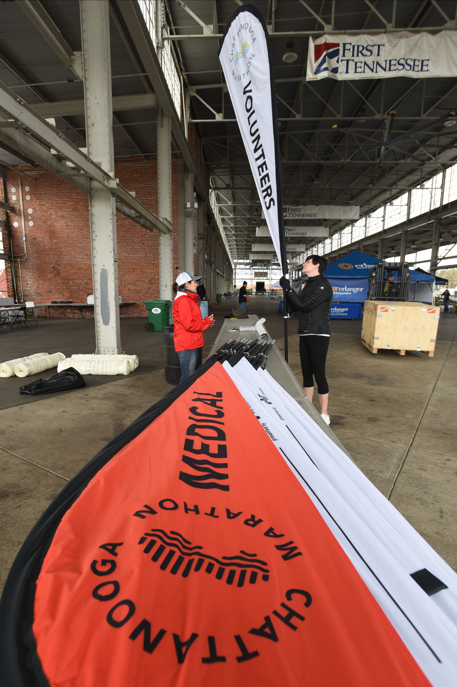 Stacey Malecky, left, and Sarah Barnes hold markers while setting up Friday, March 4, 2016 for Sunday's inaugural Erlanger Chattanooga Marathon at First Tennessee Pavilion.