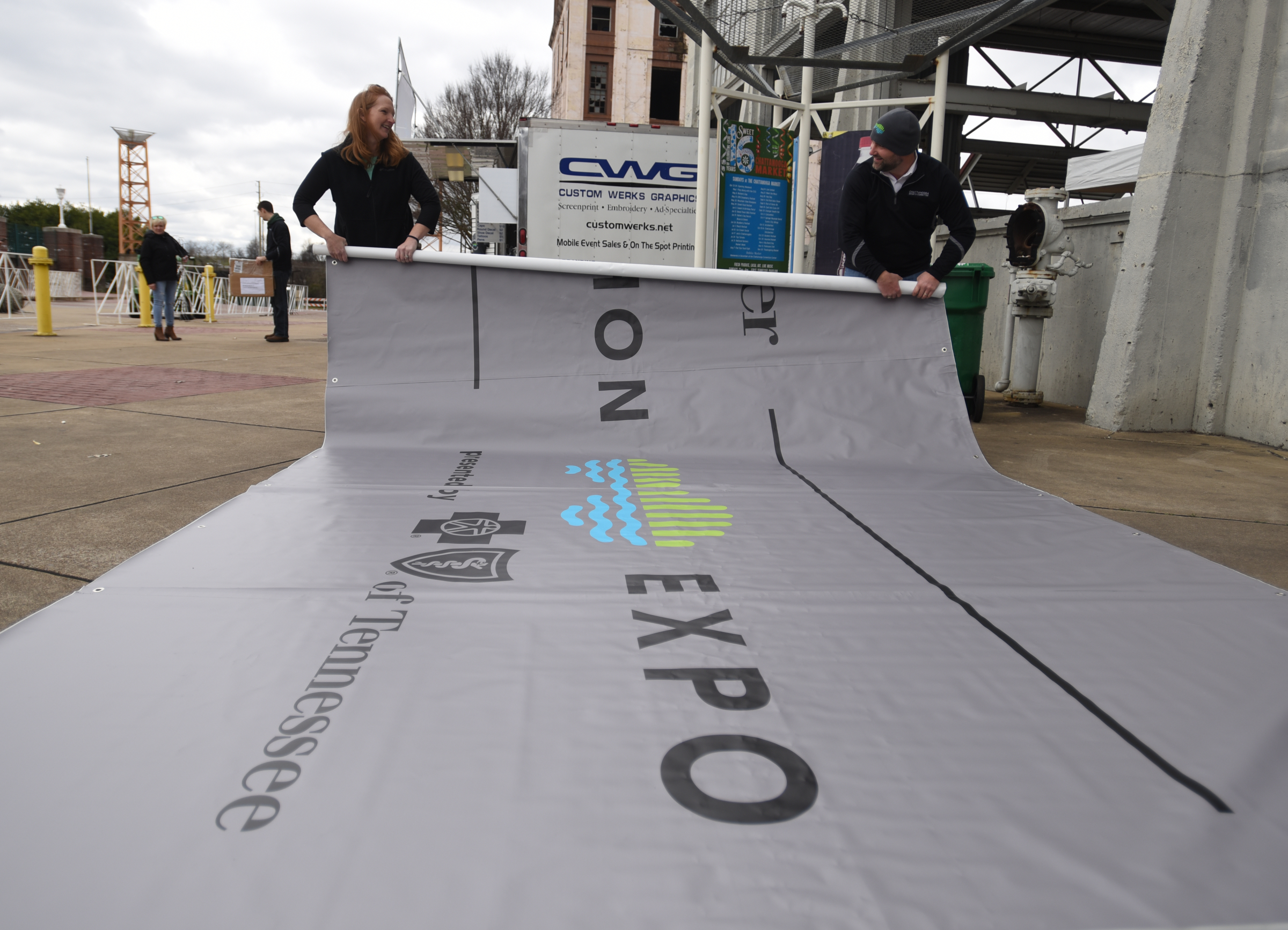Molly Cooper, left, and Tim Morgan roll up a banner while setting up Friday, March 4, 2016 for Sunday's inaugural Erlanger Chattanooga Marathon at First Tennessee Pavilion.