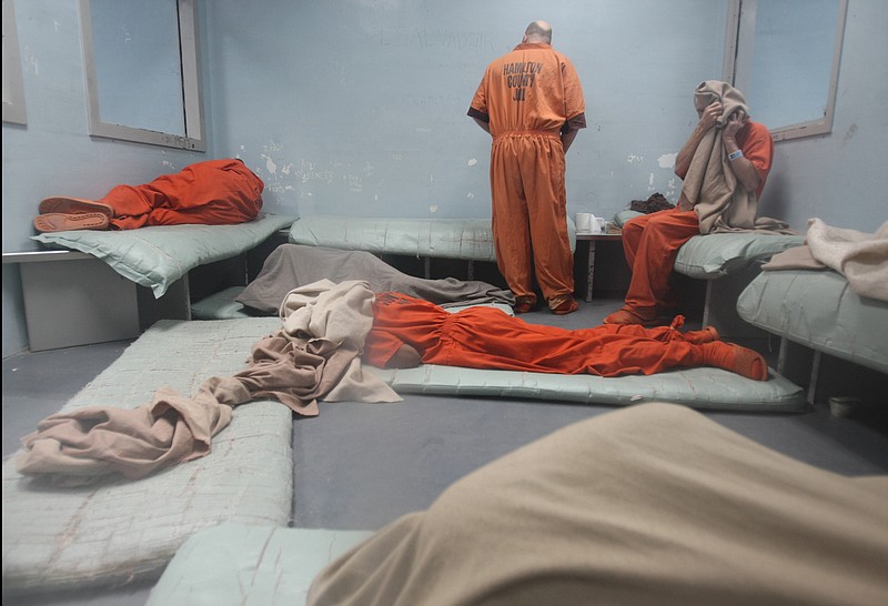 Subjects sit along the wall and lay on the floor as they wait to be assigned a cell upstairs at the Hamilton County Jail. Jail officials are currently seeking ways to alleviate overcrowding, which has been a problem for several years.