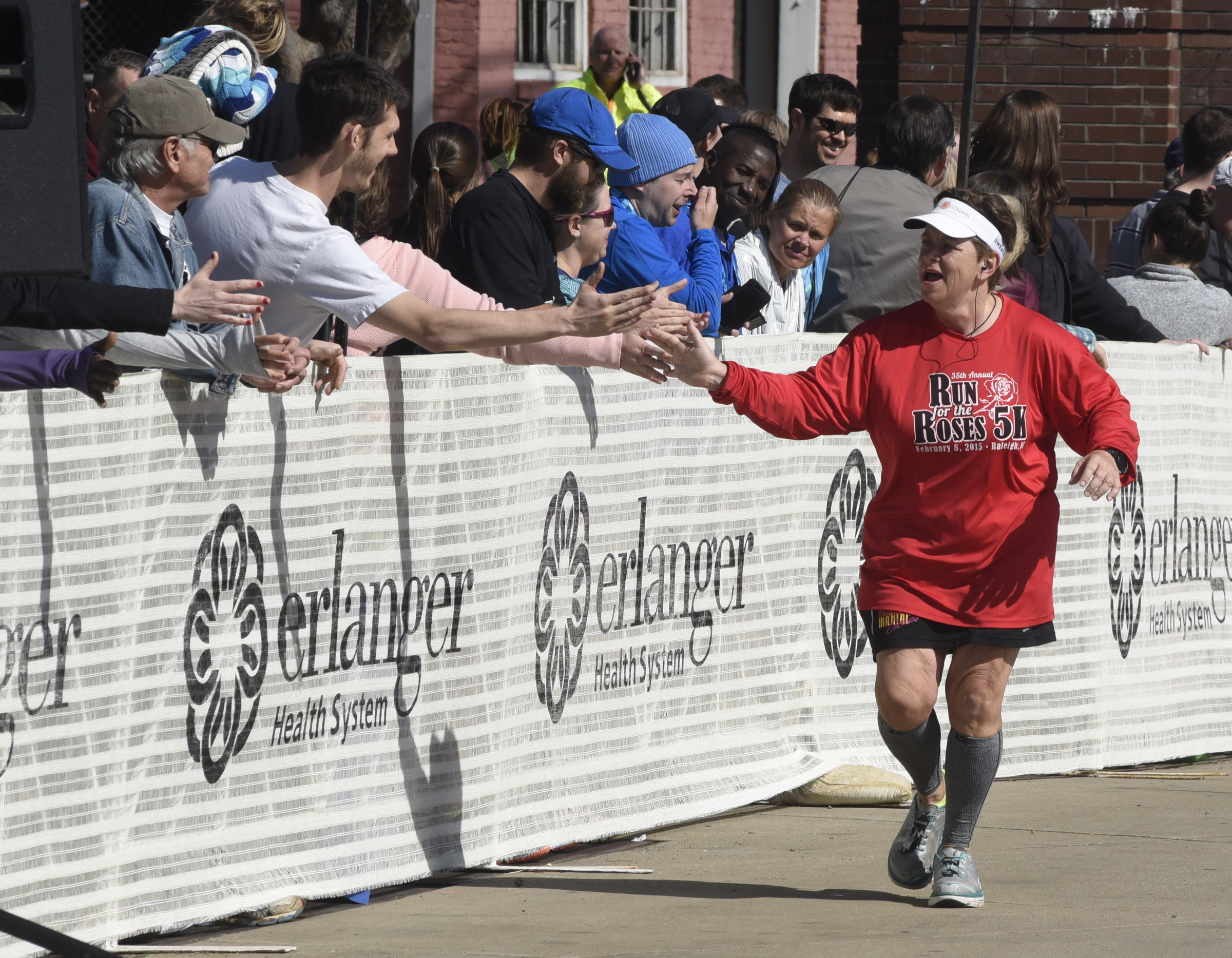 Maureen Bowen from Raleigh, N. Car., gives high-fives to spectators near the finish line at the Chattanooga Marathon on Sunday, Mar. 6, 2016, in Chattanooga, Tenn. It was the 140th half-marathon race she has completed, she said.
