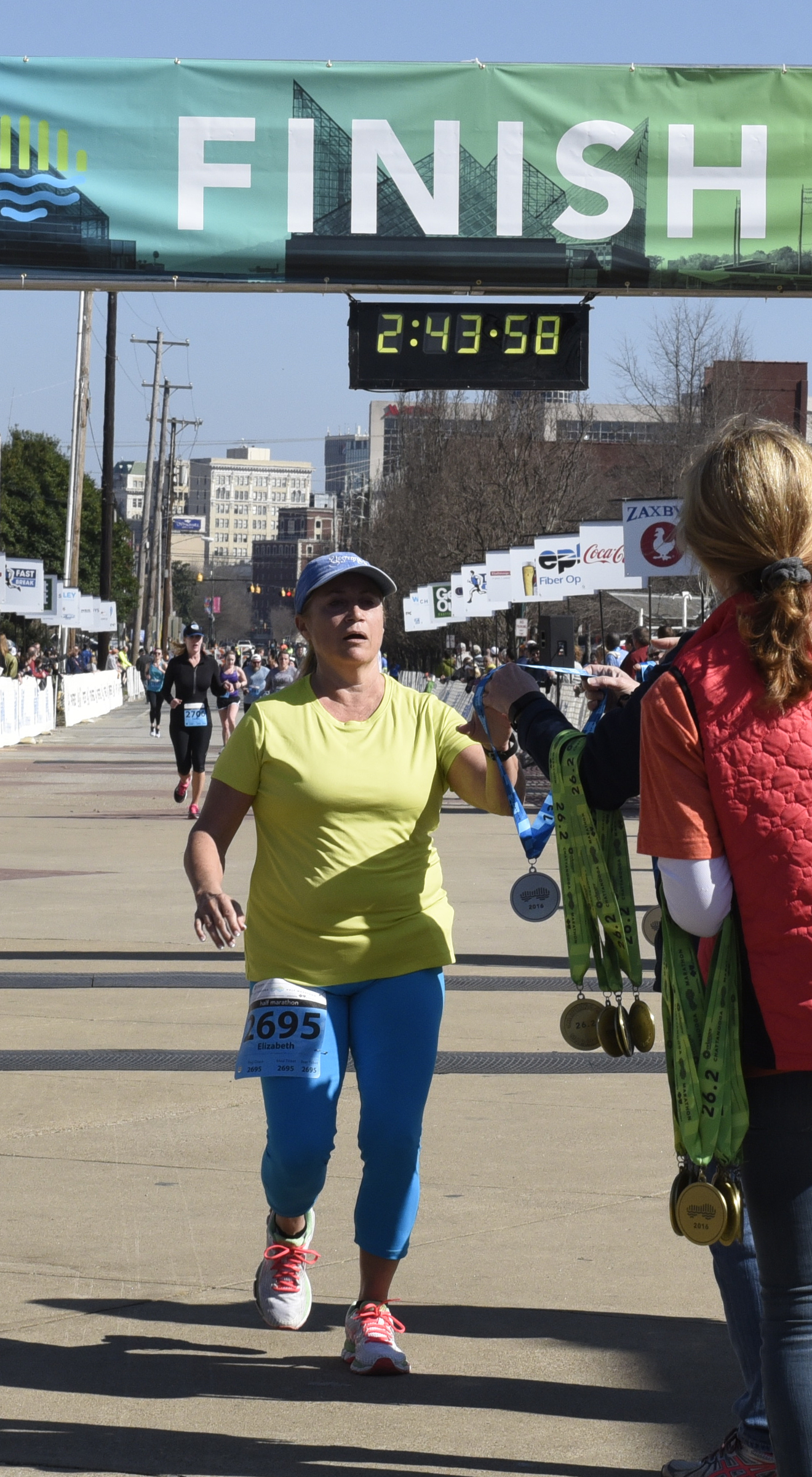 Elizabeth Miller picks up a medal as she crosses the finish line during the first running of the Chattanooga Marathon on Sunday, Mar. 6, 2016, in Chattanooga, Tenn.