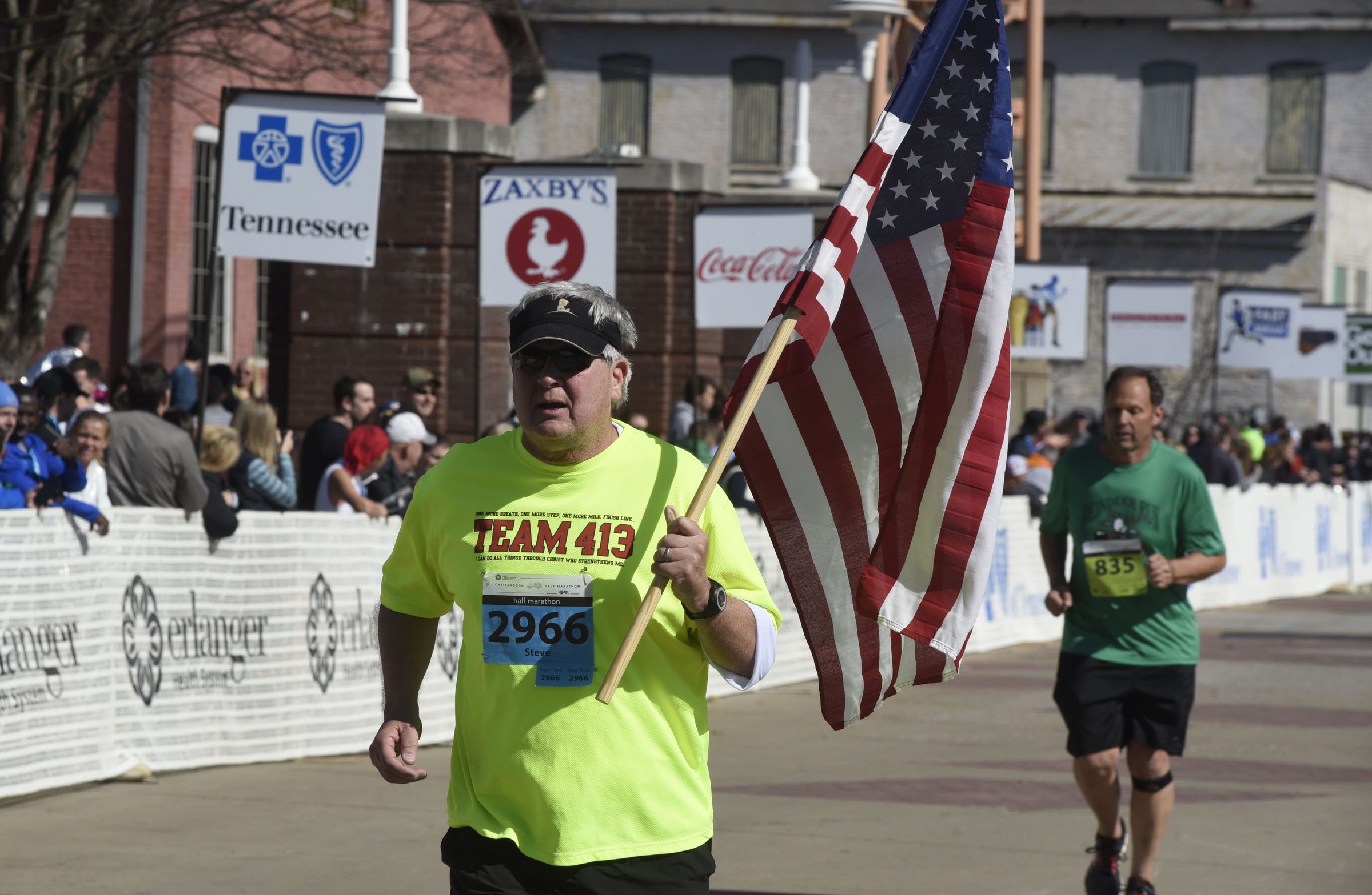 Steve Speelman, from Knoxville, carries an American flag in honor of the five servicemen killed in Chattanooga last July as he nears the finish line at the Chattanooga Marathon on Sunday, Mar. 6, 2016, in Chattanooga, Tenn.