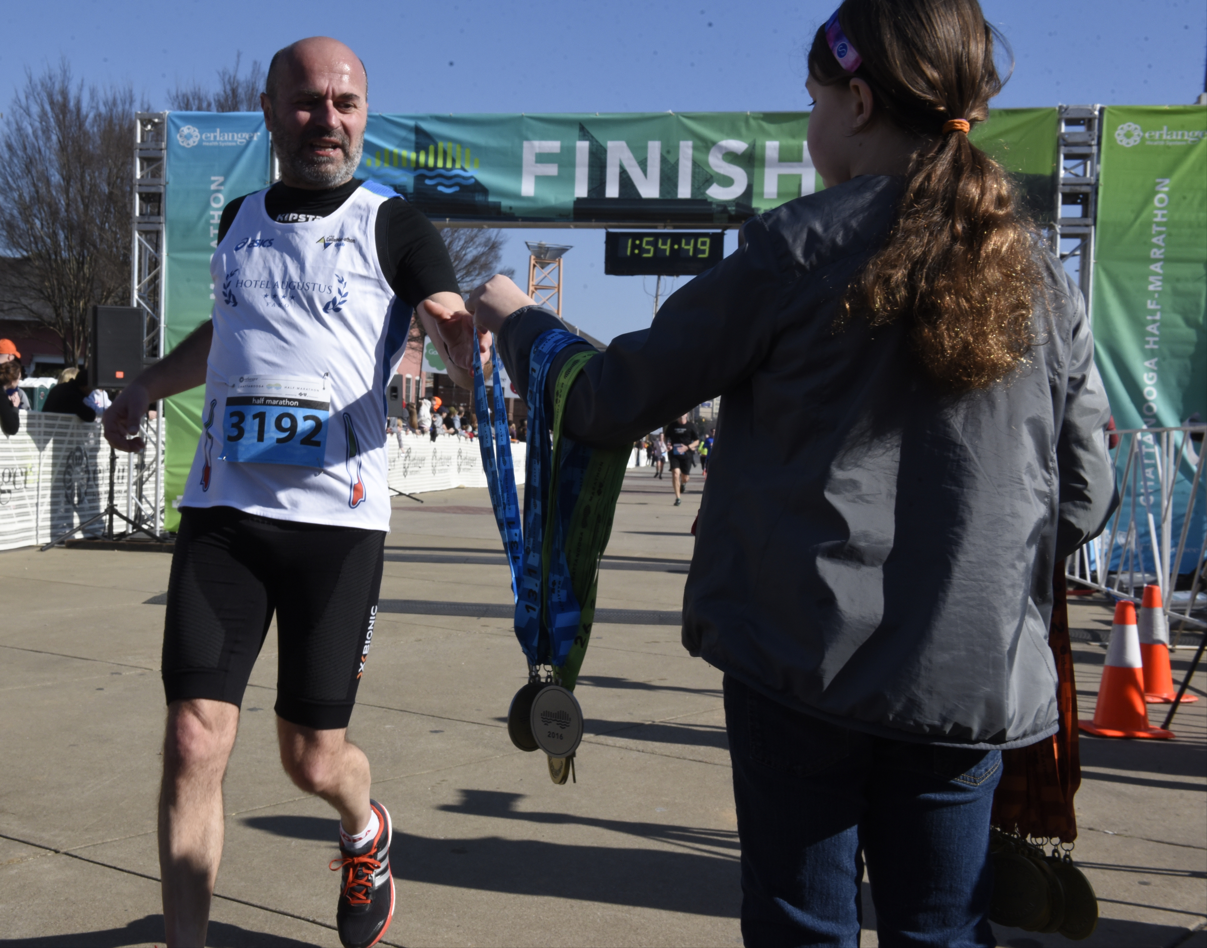 Volunteers pass out medals to participants as the cross the finish line during the first running of the Chattanooga Marathon on Sunday, Mar. 6, 2016, in Chattanooga, Tenn.