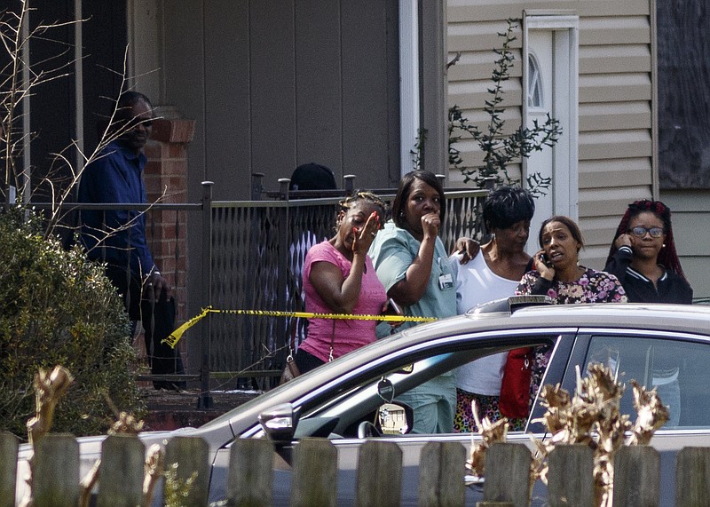 People identified by Police Department spokesperson Kyle Miller as family and neighbors of victim Michael Hines, 41, stand inside the crime scene after a homicide at 5608 Pinelawn Avenue on Wednesday, March 9, 2016, in Chattanooga, Tenn. Police said that the victim was shot and killed during a robbery.