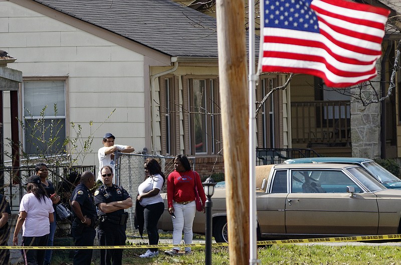 People identified by Police Department spokesperson Kyle Miller as family and neighbors of victim Michael Hines, 41, stand inside the crime scene after a homicide at 5608 Pinelawn Avenue on Wednesday, March 9, 2016, in Chattanooga, Tenn. Police said that the victim was shot and killed during a robbery.