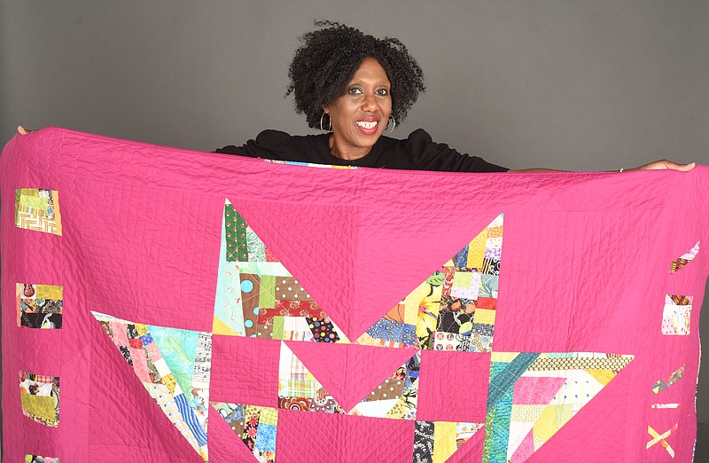 Cornelia Johnson  holds a quilt that was given to her as a housewarming present by a local quilting group. 