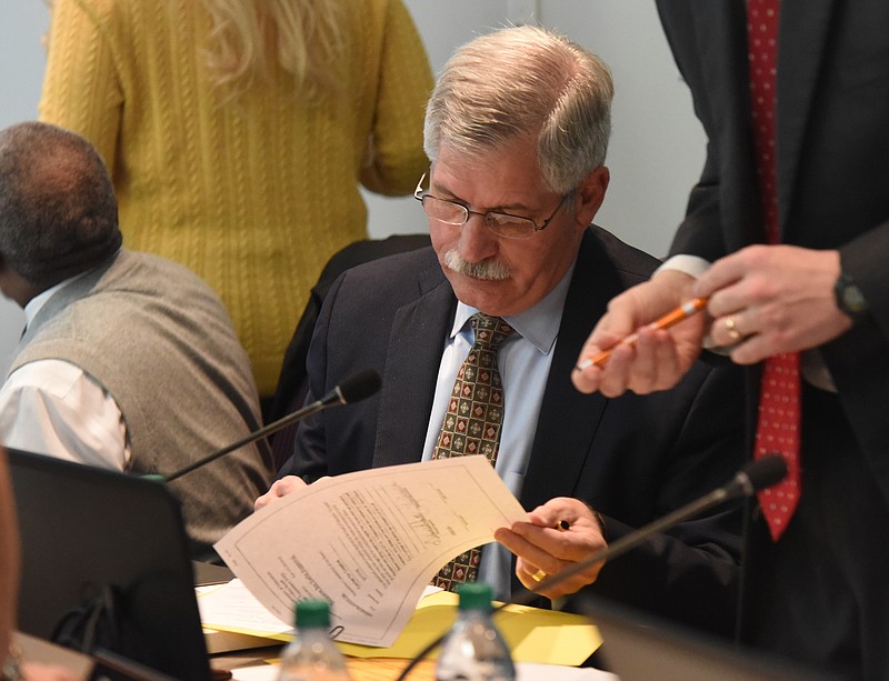 Superintendent Rick Smith signs some paperwork before a Hamilton County school board meeting in February.