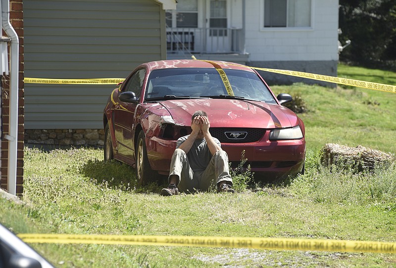 A man identified as Aaron Randal, 22, who accidentally discharged a weapon and killed a 19-year-old woman at 1206 Lewis St., holds his head in his hands as Chattanooga police investigate the shooting scene on Monday.