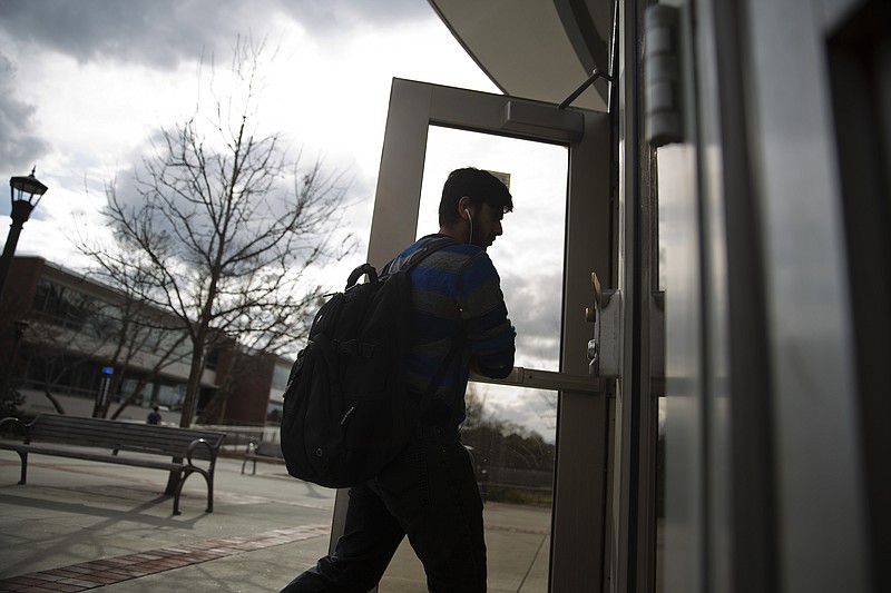 A pedestrian walks into the library on the Georgia Tech campus Friday, March 11, 2016, in Atlanta. Licensed gun owners who are 21 and older would be able to carry concealed weapons on public college campuses in Georgia if Gov. Nathan Deal signs a bill headed to his desk. The Georgia Senate passed the bill by a 37-17 vote on Friday, bidding to legalize concealed firearms on campuses statewide. 