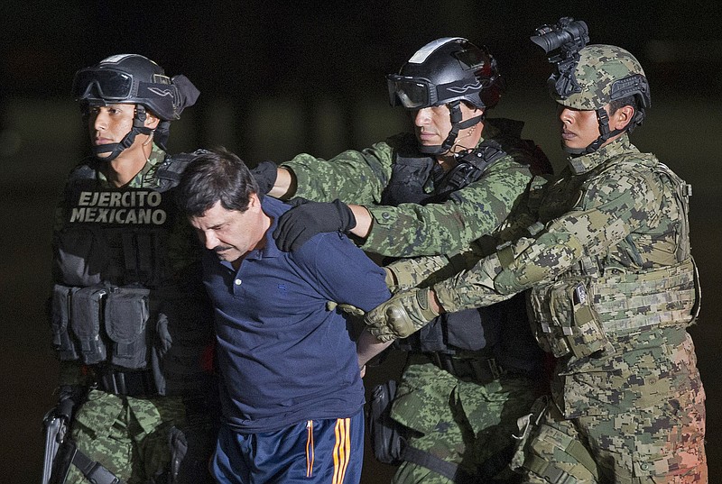 In this Jan. 8, 2016 file photo, Mexican army soldiers escort drug lord Joaquin "El Chapo" Guzman to a helicopter to be transported to a maximum security prison at Mexico's Attorney General's hangar, in Mexico City. Things were a lot different for Guzman the last time he was in prison, after being captured the second time in 2014. which according to a court filing shared by his lawyers, Guzman described as a relatively permissive environment with plenty of access by outside visitors and some freedom to move around. (AP Photo/Eduardo Verdugo, File)