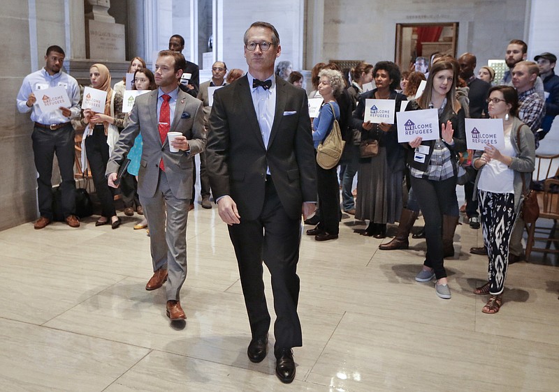 Sen. Bo Watson, center, R-Hixson, walks past demonstrators opposed to immigration restrictions outside the Senate Chamber on Monday, Feb. 22, 2016, in Nashville. The state Senate has passed a resolution on a 27-5 vote directing Tennessee's attorney general to mount a legal challenge to the federal refugee resettlement program. 