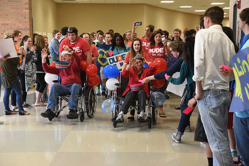 Bobby Hunt, left, custodian, and Adelina "Ling-Ling" Corle, cafeteria worker, are wheeled down the hall Thursday as adoring students honor them at Heritage High School on Thursday.