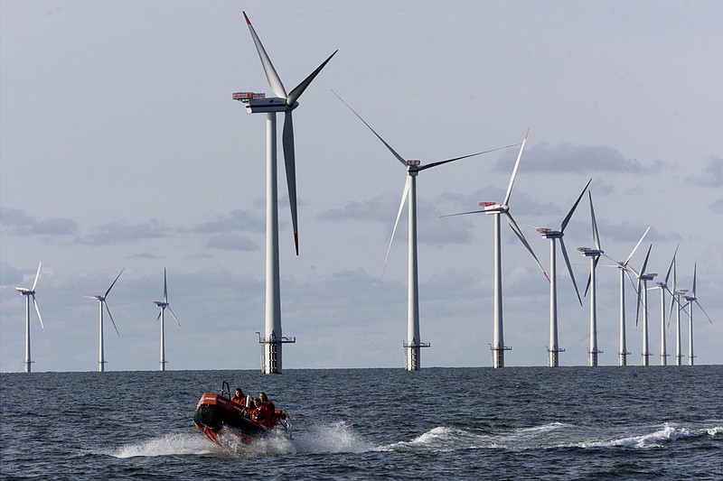 A speed boat passes offshore windmills in the North Sea off the country of Denmark.