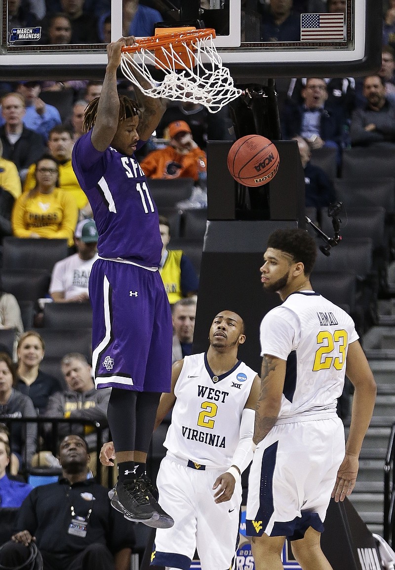 
              Stephen F. Austin's Clide Geffrard, Jr. (11) dunks the ball as West Virginia's Esa Ahmad (23) and Jevon Carter (2) react during the first half of a first-round men's college basketball game in the NCAA Tournament,Friday, March 18, 2016, in New York. (AP Photo/Frank Franklin II)
            