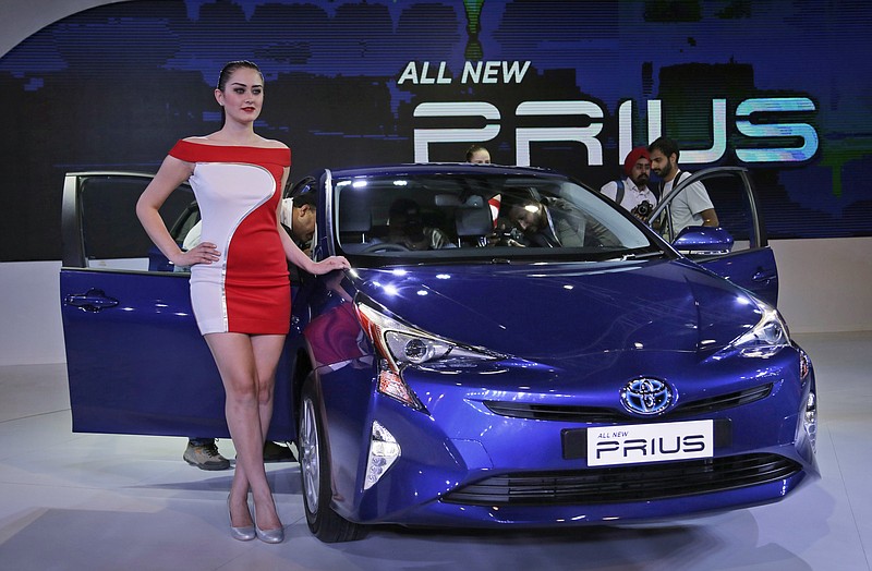 In this Thursday, Feb. 4, 2016, file photo, a model poses next to Toyota's fourth-generation Prius hybrid car at the Auto Expo in Greater Noida, near New Delhi, India. (AP Photo/Altaf Qadri, File)