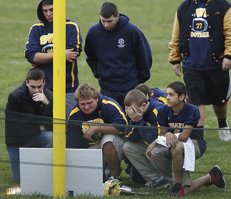 Shoreham Wading River football players gather at a makeshift memorial for Tom Cutinella on the high school's field on Oct. 2, 2014, in Shoreham, N.Y. Cutinella died the day before at the age of 16 from a collision in a game against John Glenn High School.