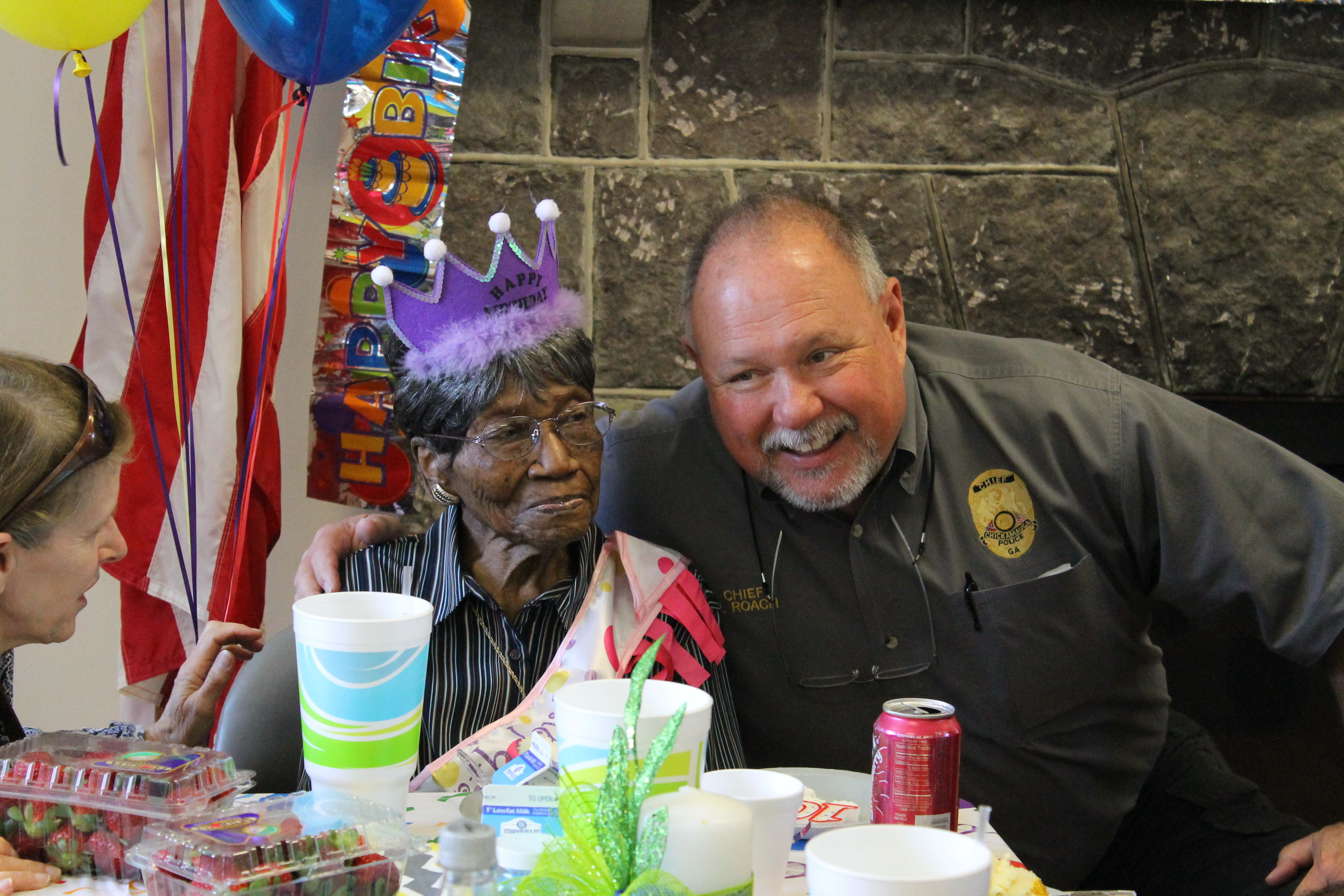 Chickamauga Police Chief Ronald Roach, right, hugs Jerrel Dean Hudgins at her 100th birthday party at the Chickamauga Active Living Center. She attributes her long life to God.