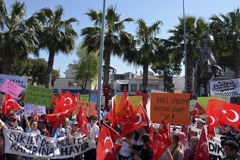 
              Residents wave national flags as they protest against plans to build a refugee camp under the new EU-Turkey deal in Aegean resort of Dikili, Izmir, Turkey, Saturday, April 2, 2016.  Under the new deal refugees and migrants who arrived on Greek islands after March 20 will be sent back to Turkey starting on Monday. The banner reads: " We don't want a refugee camp in Dikili! "(AP Photo)
            