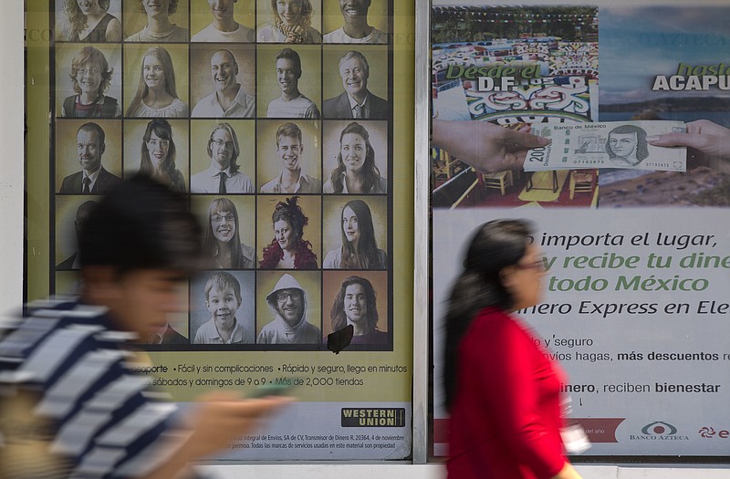 
              People walk past signs advertising money transfer services outside a business in Mexico City, Tuesday, April 5, 2016. U.S. Republican Presidential frontrunner Donald Trump is threatening to block billions of dollars in U.S. remittances to force Mexico to pay for his proposed border wall. (AP Photo/Rebecca Blackwell)
            