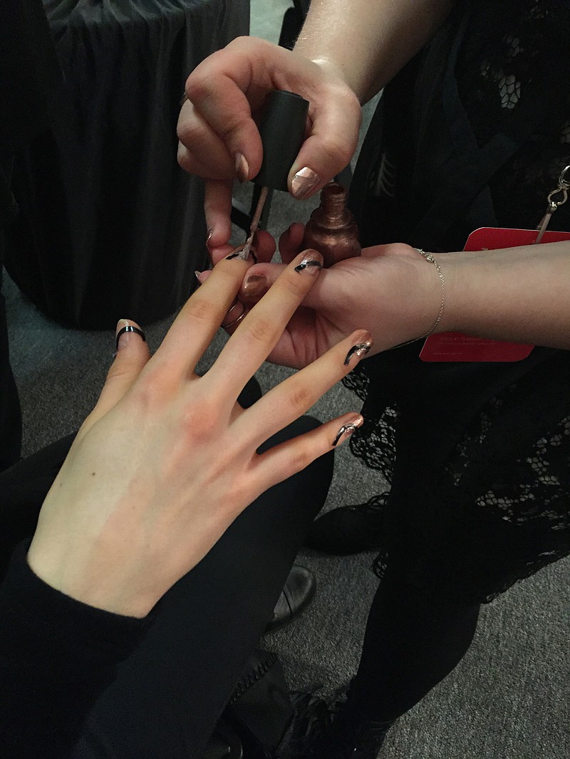 A nail technician completes a manicure.