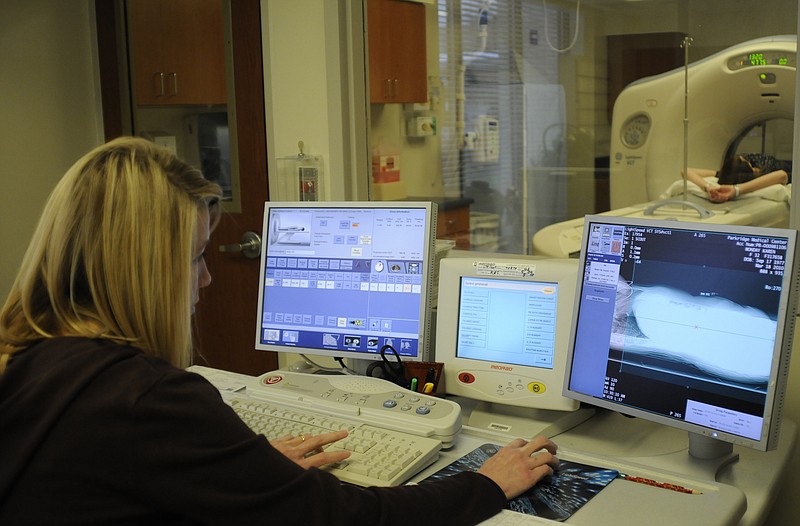 A technician monitors a patient during a CT scan in this file photo.