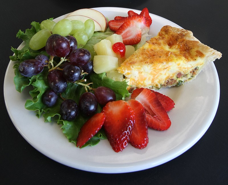 Quiche Lorraine is served with a fresh fruit salad.