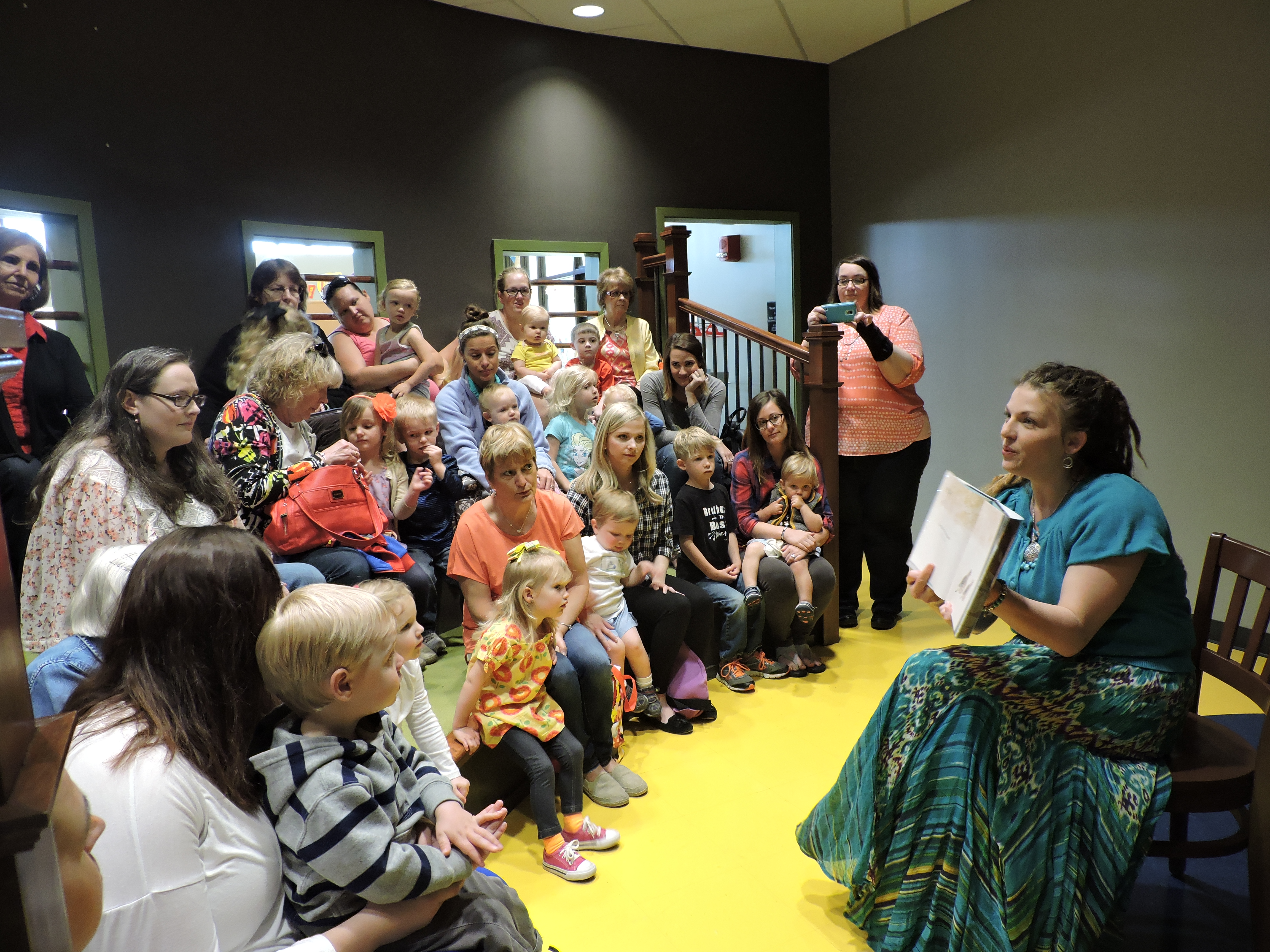 LaFayette High School art teacher Heather Hawkins-Parker reads a book about birds nesting during children's hour at the unveiling of the new mosaic tree that welcomes guests to the Children's Department at the LaFayette-Walker County Library.