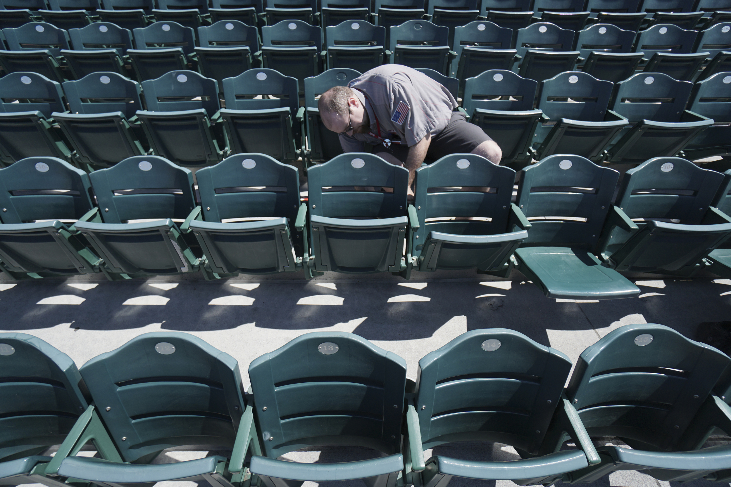 Staff Photo by Dan Henry / The Chattanooga Times Free Press- 4/5/16. Jeremy Culbert affixes new cupholder stickers on the bleachers at AT&T field on April 5, 2016.