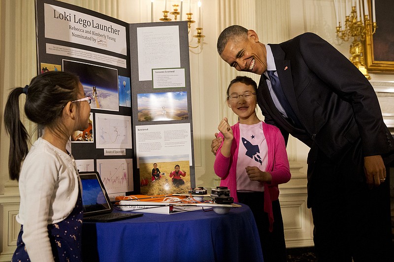 
              President Barack Obama laughs as he hugs Rebecca Yeung, 11, from Seattle, Wash., next to her sister Kimberly Yeung, 9, as they show him their homemade “spacecraft” that features a photograph of their late cat and is made of archery arrows and wood scraps  which they launched into the stratosphere via a helium balloon that records location coordinates, temperature, velocity, and pressure and reports the data back to the them, Wednesday, April 13, 2016, during the 2016 White House Science Fair at the White House in Washington. (AP Photo/Jacquelyn Martin)
            
