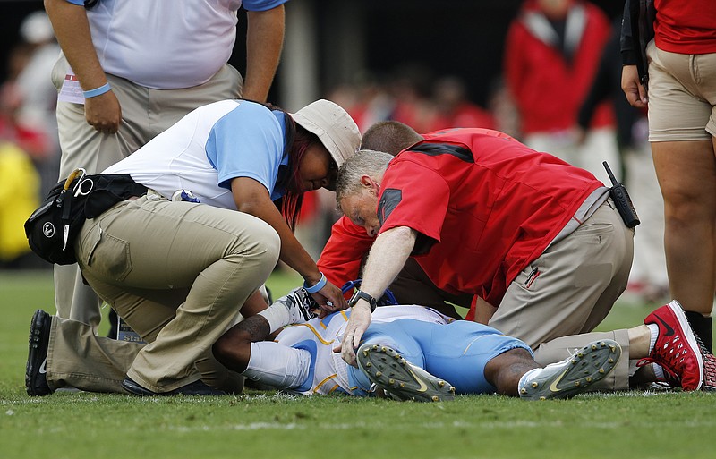 Members of the Southern and Georgia training staff tend to Southern wide receiver Devon Gales (33) after he was injured in the second half of an NCAA college football game against Georgia  Saturday, Sept. 26, 2015, in Athens , Ga. Gales was placed on backboard and taken off the field on a cart. (AP Photo/John Bazemore) 
