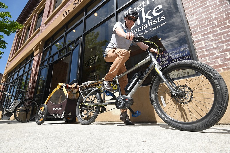 Electric Bike Specialists Owner Chandlee Caldwell prepares to take his dog, Archie, for a ride on his electric bike and trailer from the East Main Street shop.
