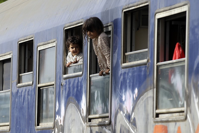 
              Children peer out from train carriage windows near a makeshift camp at the northern Greek border point of Idomeni, Greece, Tuesday, April 19, 2016. More than 11,000 people have been waiting at this border point for over a month hoping it would reopen. (AP Photo/Gregorio Borgia)
            