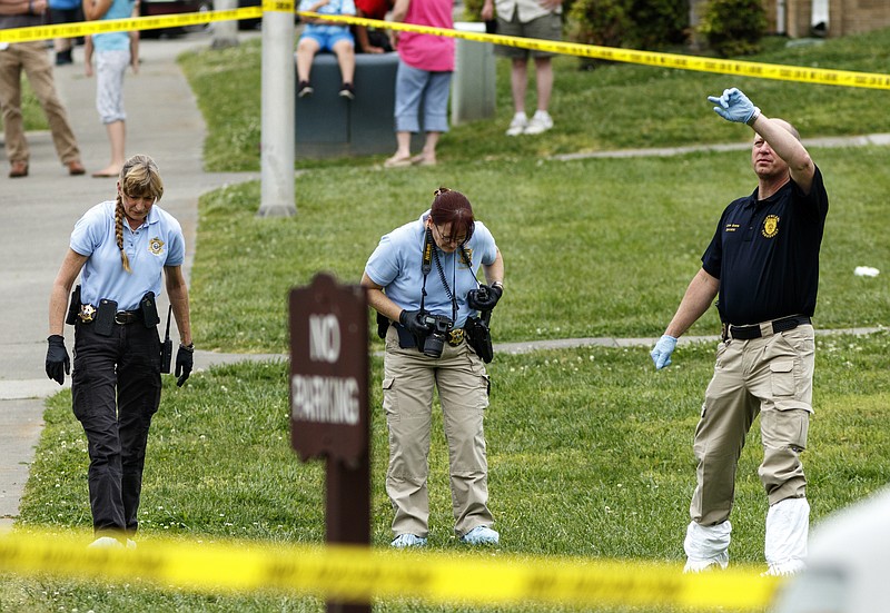 Investigators search for evidence at the scene after a triple-stabbing at Springbrook Apartments on Thursday, April 21, 2016, in Cleveland, Tenn. Two are dead and a third critically wounded in the stabbing, and Cleveland police say a suspect is in custody.
