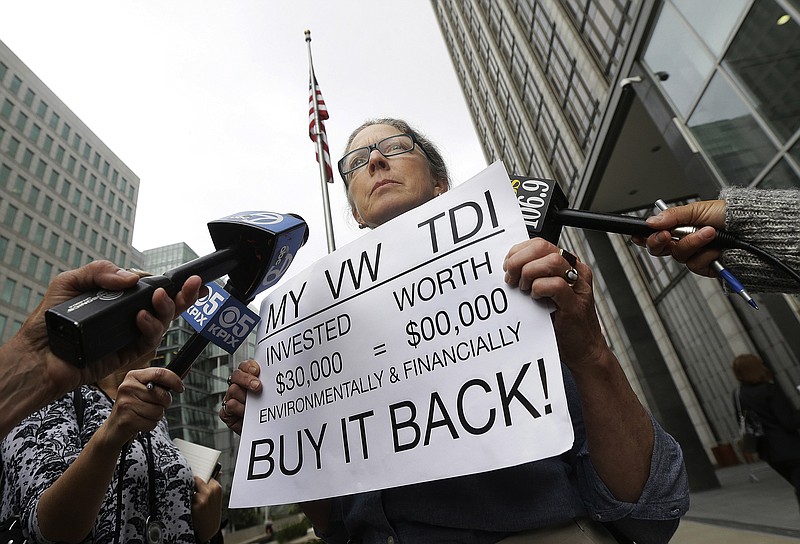 
              Joyce Ertel Hulbert, owner of a 2015 Volkswagen Golf TDI, holds a sign while interviewed outside of the Phillip Burton Federal Building in San Francisco, Thursday, April 21, 2016. An agreement will give consumers who bought nearly 600,000 Volkswagen vehicles rigged to cheat on emissions tests the option of having the automaker buy back the cars or fix them, a judge said Thursday. (AP Photo/Jeff Chiu)
            