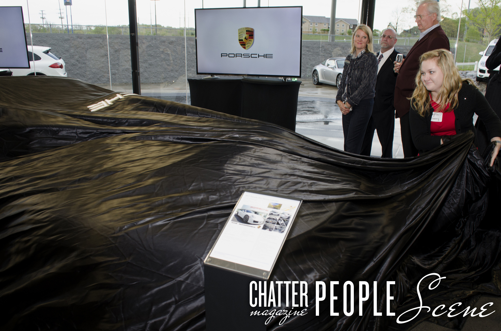 Payton Mowery pulls the cover to reveal the 2017 Porsche 911 while dealership owner Sam Furrow and Lee Ann Furrow Tolsma look on with manager James van der Merwe