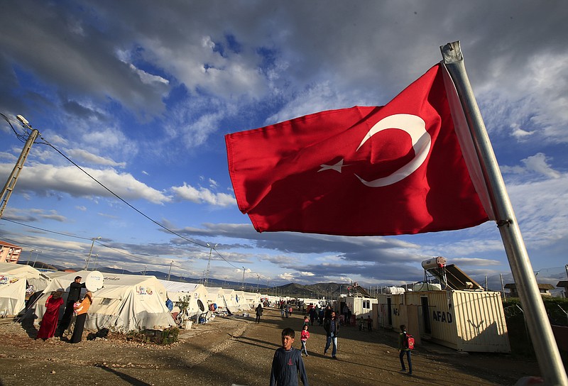 
              FILE - In this Wednesday, March 16, 2016 file photo a Turkish flag flies at the refugee camp for Syrian refugees in Islahiye, Gaziantep province, southeastern Turkey.  German Chancellor Angela Merkel and top European Union officials plan to travel close to Turkey’s border with Syria in hopes of promoting a troubled month-old agreement to manage a refugee crisis that has left hundreds of thousands stranded on the migrant trail to Europe. (AP Photo/Lefteris Pitarakis, File)
            