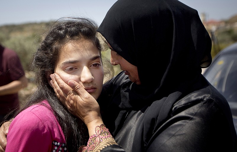 
              Sabha al-Wawi, right, Palestinian mother of 12-year-old Dima al-Wawi, imprisoned by Israel for allegedly attempting to carry out a stabbing attack, comforts her daughter, after her release from an Israeli prison, at Jabara checkpoint near the West Bank town of Tulkarem, Sunday, April 24, 2016. Al-Wawi who was imprisoned after she confessed to planning a stabbing attack in a West Bank settlement has been released Sunday. (AP Photo/Majdi Mohammed))
            