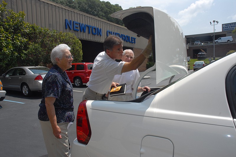 Staff Photo by Tim Barber In this file photo, Newton Chevrolet sale representative Dwayne Pruitt, center, shows Nola and Frank Rogers the emergency truck release on a 2006 Chevrolet Malibu.