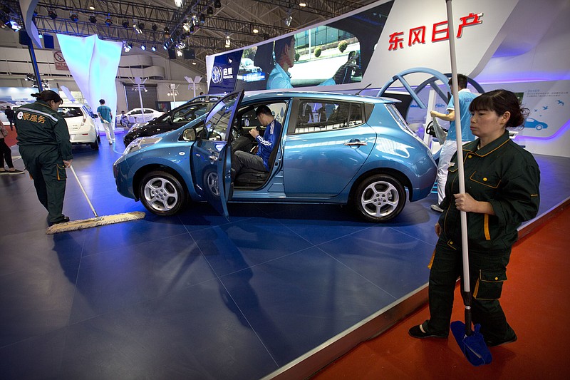 
              Workers clean the floor around a Morning Wind electric car from Chinese automaker Venucia on display at the Beijing International Automotive Exhibition in Beijing, Monday, April 25, 2016. (AP Photo/Mark Schiefelbein)
            