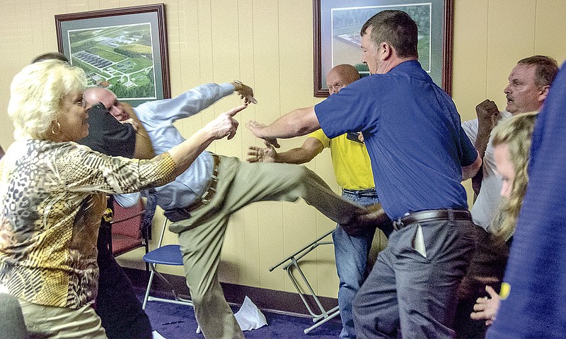 Alexander City, Ala., Mayor Charles Shaw, left, is restrained by an officer after a fight broke out between him and councilman Tony Goss, far right, during a meeting of the Alexander City City Council in Alexander City, Ala., on Monday, April 25, 2016.