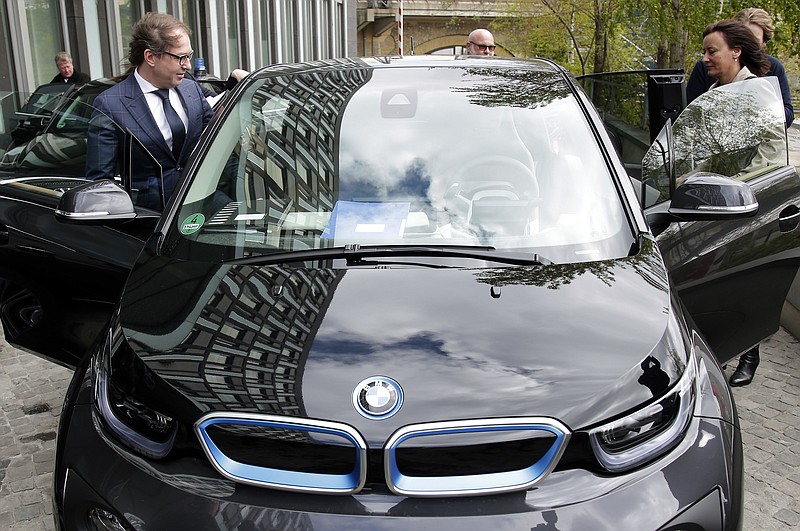 
              German Transportation Minister Alexander Dobrindt, left, and his staff members get on the minister's e-car after a press conference in Berlin, Germany, Wednesday, April 27, 2016. Germany plans to subsidize electric cars in a bid to help the country's auto industry compete in the global market for the growingly-popular and environmentally friendly vehicles. (AP Photo/Michael Sohn)
            