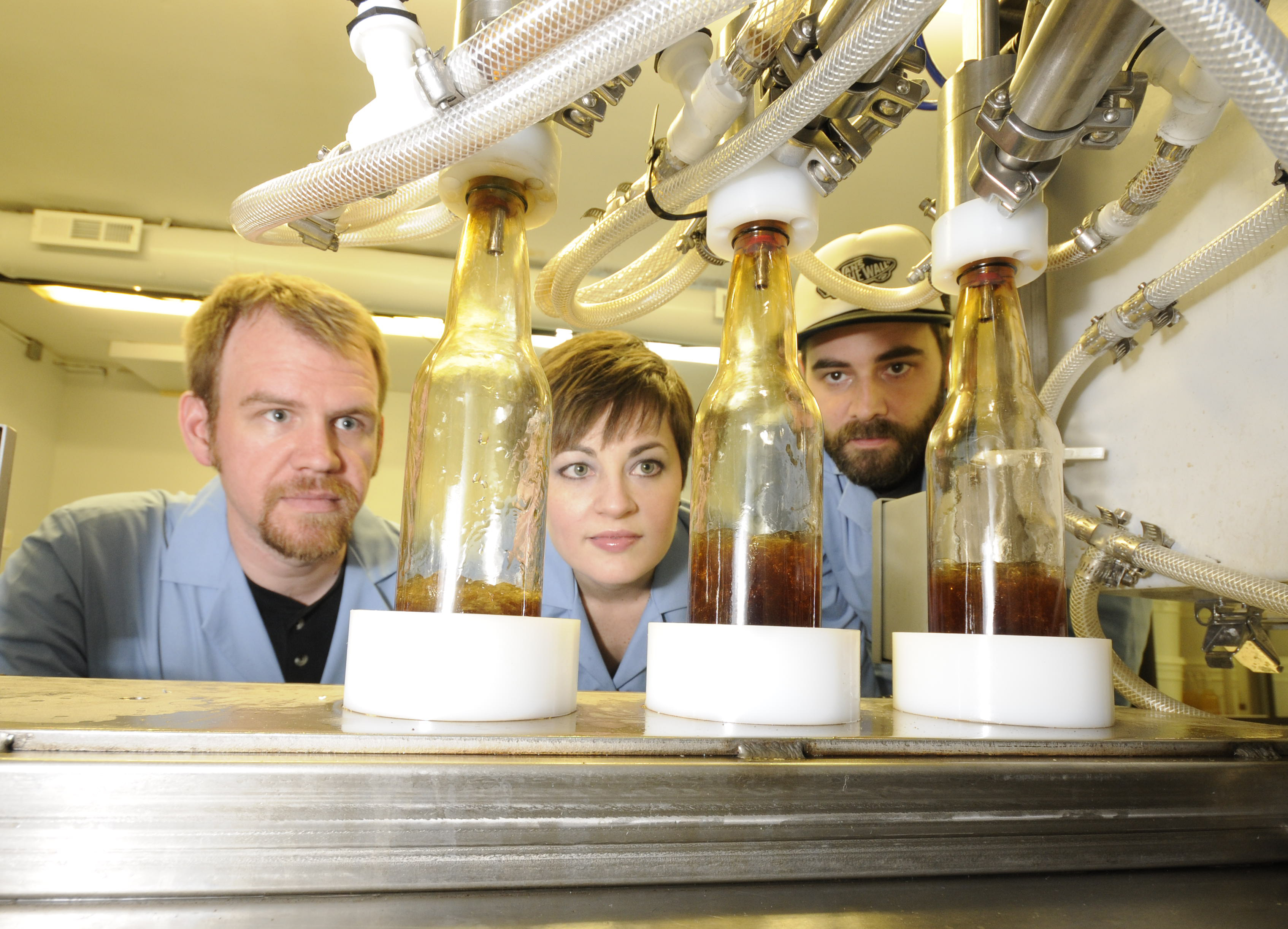 Matt Rogers, Tiffany Rogers and Shawn Clouse watch as their Cafe Cola mixture is bottled in the Pure Sodaworks lab on the Northshore. Pure Sodaworks' custom bottling machine was purchased using funds generated during a Kickstarter campaign that was recently named a Project We Love by the crowdfunding site.