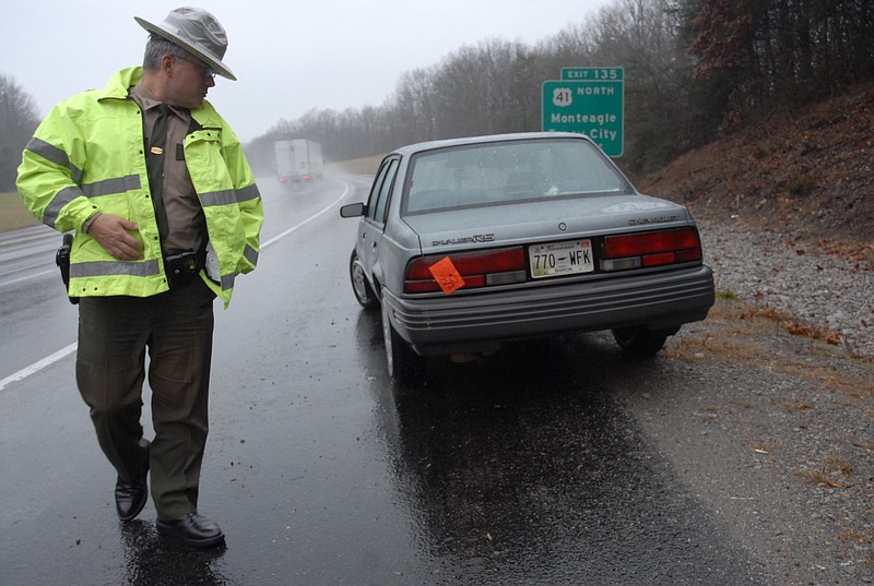 In this file photograph from December 2009, THP Trooper Butch Reeves inspects an abandoned car in the rain atop Monteagle Mountain in Marion County, Tenn.