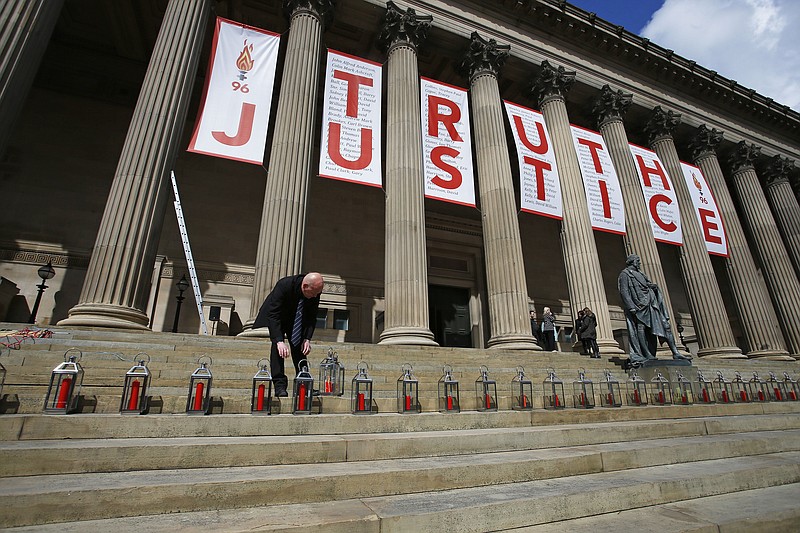 
              A man places candles for each of the 96 Liverpool fans who died as a result of the Hillsborough disaster at St George's Hall in Liverpool, England, Wednesday, April 27, 2016. Liverpool is commemorating the deaths of 96 soccer fans crushed to death in a crowded stadium in 1989 after a jury found that blunders by police and emergency services contributed to their deaths. (Peter Byrne/PA via AP) UNITED KINGDOM OUT  
            